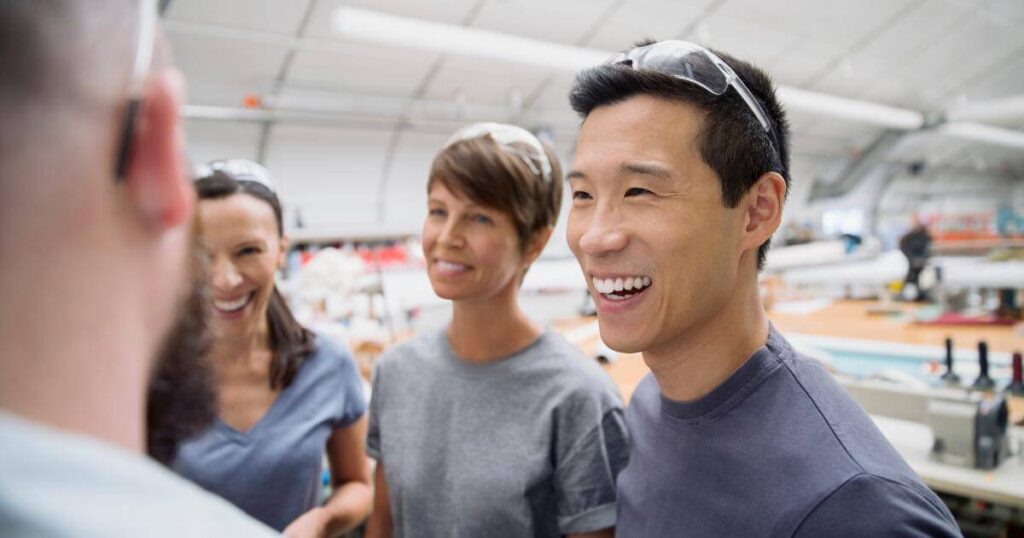 Manufacturing workers smiling on the floor — how a positive workplace culture helps attract top talent in Oregon