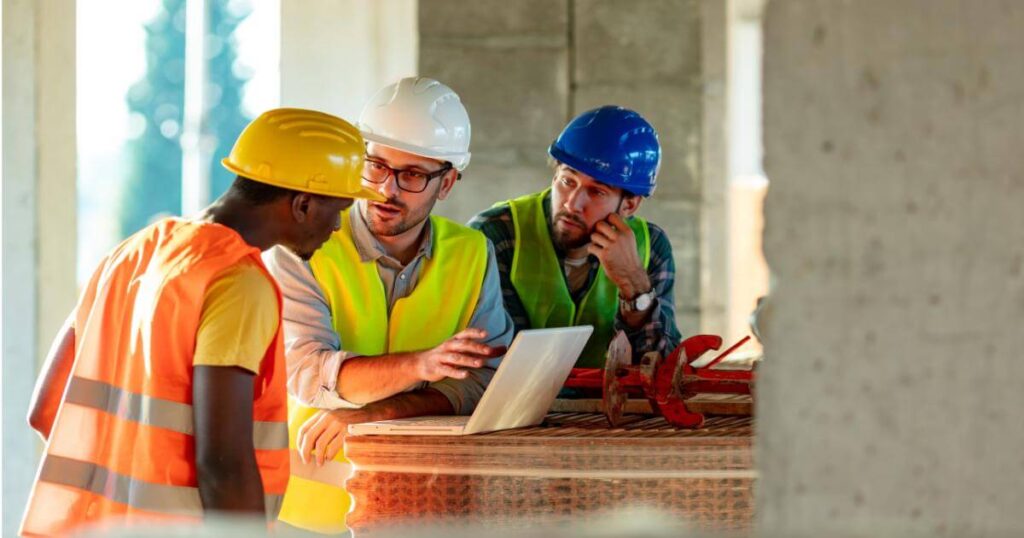 two construction workers coaching another worker