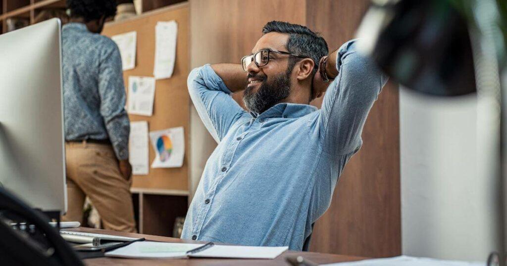 smiling manager leaning back with hands behind head