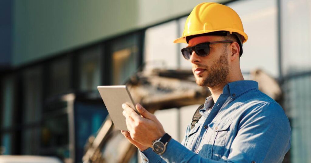 Oregon construction contractor reviewing hiring needs on a tablet at a job site